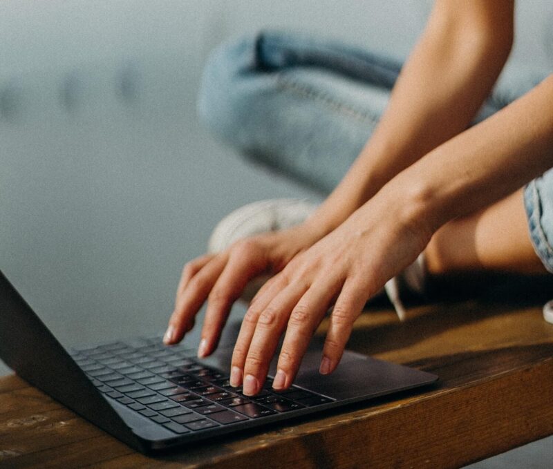 Person is typing on their keyboard while sitting cross-legged on the floor.